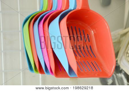 colorful plastic cat litter shovel hanging on hook displays in pet shop