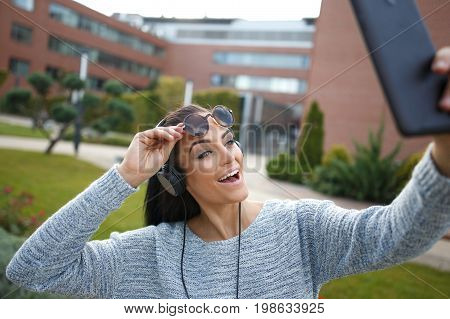 Woman taking selfie with tablet in park making expression