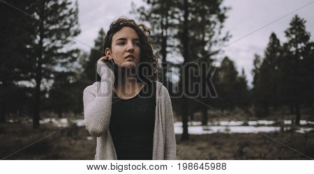 Smiling and nice caucasian girl in a warm cardigan standing outdoors in nature at day time. She is enjoying with this cold but pleasant day. Close up