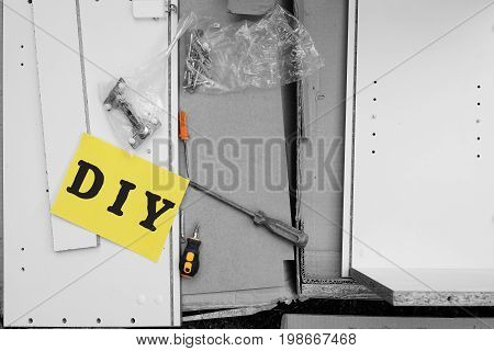 Unboxed parts of furniture with work tools and badge Do It Yourself on a top selective color photo