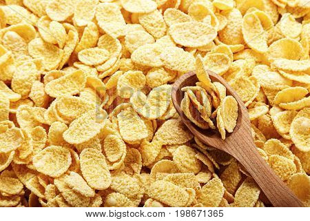 Cornflakes in brown scattered as a background in flakes a wooden spoon