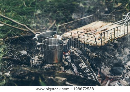 top view on bonfire with chicken meat and cup with water