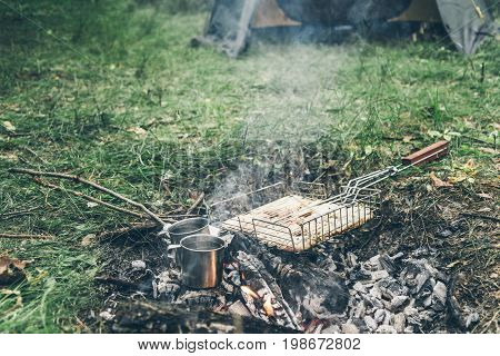 top view on bonfire with chicken meat and cup with water