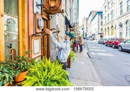 Montreal Canada - May 28 2017: Man changing restaurant menu outside by sidewalk in morning by street during day outside entrance in Quebec region city