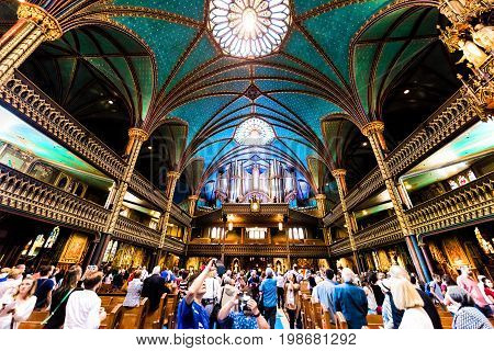 Montreal Canada - May 28 2017: Inside Notre Dame Basilica during mass with many people taking pictures of detailed architecture and organ