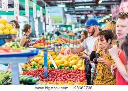 Montreal Canada - May 28 2017: People trying samples and buying produce by fruit and vegetable stands at Jean-Talon farmers market with tomato displays