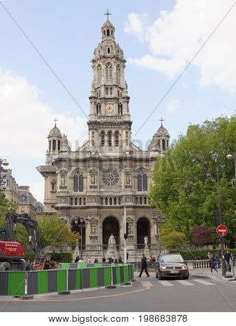 ParisFrance- April 29 2017: View of the Cathedral of the Holy Trinity on the Square d'Estienne d'Orves. On the street pedestrians and moving vehiclesworking excavator