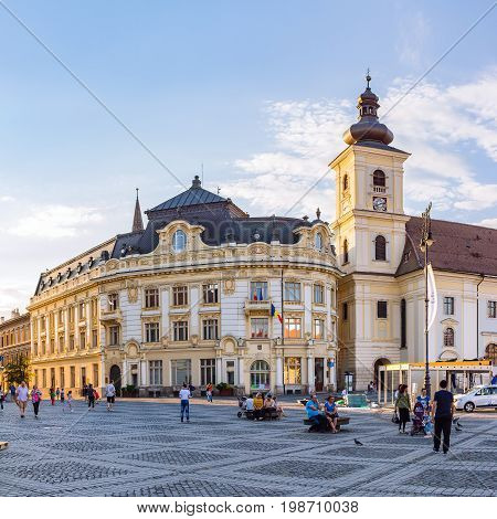SIBIU ROMANIA - JUNE 19 2017: Large main square Huet with City Hall Catholic Church tourists on the street ancient medieval city.