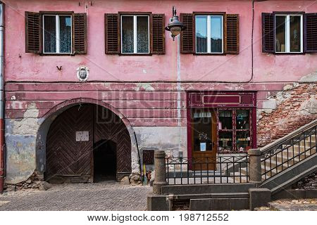 Detail of facade with wooden arch doors and windows in neglected ancient house in Sibiu city Romania.