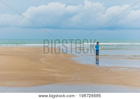 Prachuap Khiri Khan, Thailand - April  6, 2017: Asian woman (unidentified) walks along the beach in Prachuap. Weekend trips to Prachuap Khiri Khan is getting more and more popular among Thai tourists