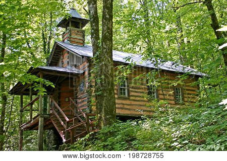 an old, log church sits on a hill deep in the woods