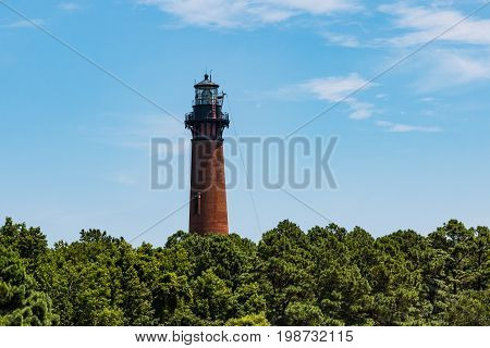 COROLLA, NORTH CAROLINA - JULY 14, 2017:  Built in 1875, and undergoing renovations, the Currituck Beach Lighthouse towers above a forest canopy, providing panoramic views of the Currituck Sound.
