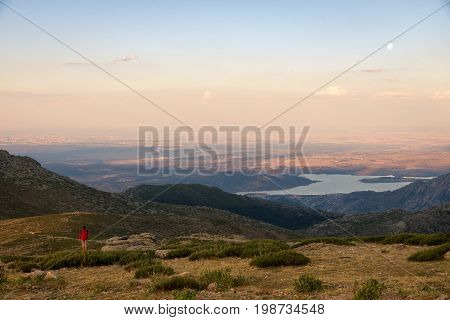Girl climber contemplates from the top of the mountain a amazing sunset and the moonrise. Navacerrada Spain.