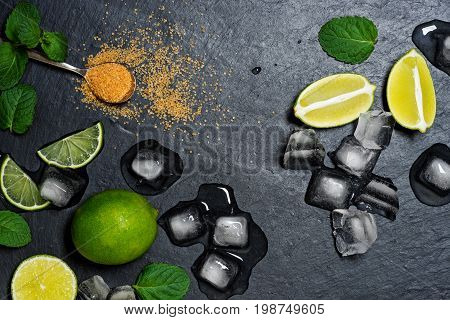 Refreshing mint cocktail mojito ingredirnts, cold drink or beverage with ice on black background, top view
