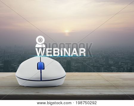 Webinar icon with wireless computer mouse on wooden table over modern city tower at sunset vintage style Seminar online concept