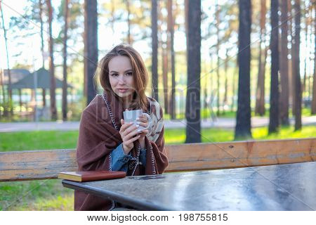 girl in a plaid drinking coffee in the park