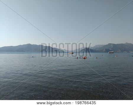 Beatiful sea summer panorama.  Beach scene at Pukka region, yachts, boats, mountains, shot at Marmaris, Turkey. blue sky, tourists in swimsuits, umbrellas, people resting, swimming