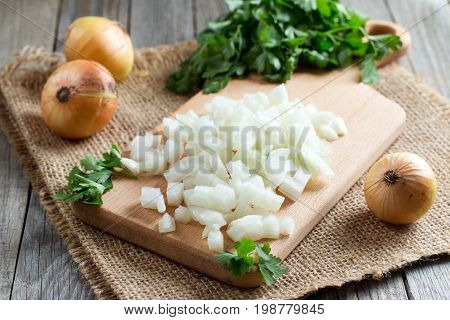 Chopped onions on wooden cutting board on the table