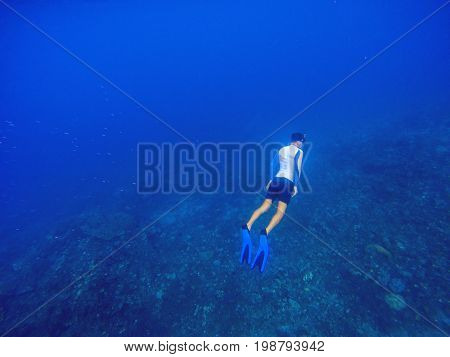 Freediver underwater in deep blue sea. Snorkeling man dives up to water surface. Open water diving lesson. Beautiful ocean deep open water. Diver man silhouette undersea photo. Sea landscape view