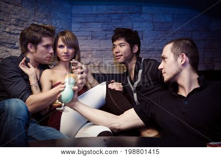 a pretty young woman is surrounded by three men trying to seduce her.