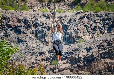 Ukraine Migea - July 30 2017: Zipline. The woman in the equipment slides on a steel cable. Trolley Track Over the lake. Extreme and active rest.