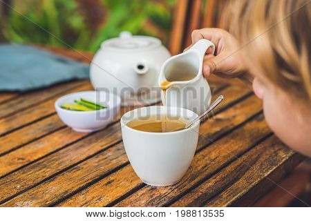 Happy Nice Boy Pours Honey Into The Tea In Summer Green Garden. Portrait. Outdoor
