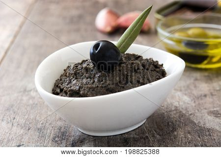 Black olive tapenade with anchovies, garlic and olive oil on wooden table