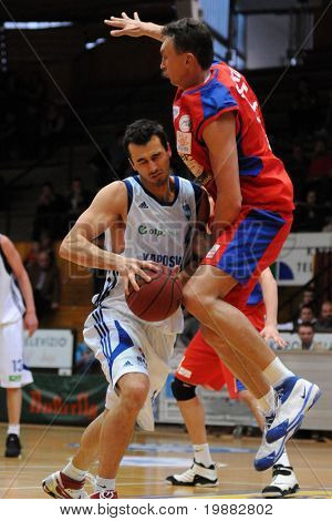 KAPOSVAR, Ungarn - APRIL 16: Erno Sitku (med rødt) i aktion på en Hugarian Champonship basketball spil.