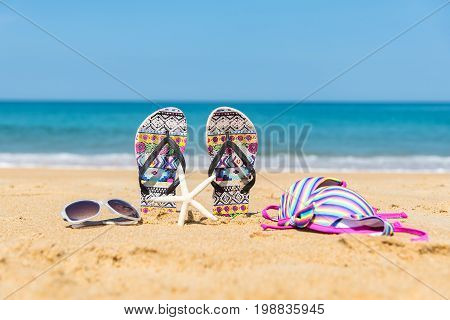 bikini swimming set hang on the wooden grub laying on the sand of the beach with the sea in background
