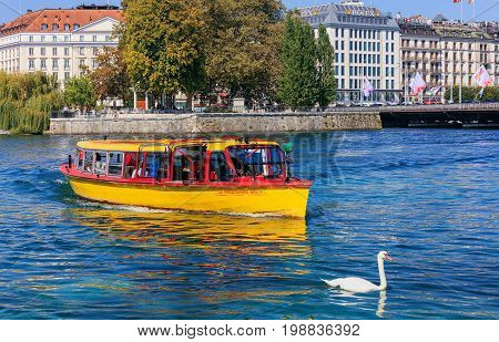 Geneva, Switzerland - 24 September, 2016: a yellow boat on the Rhone river, buildings along the river in the city of Geneva. The city of Geneva is the capital of the Republic and canton of Geneva, being the second most populous city in Switzerland.