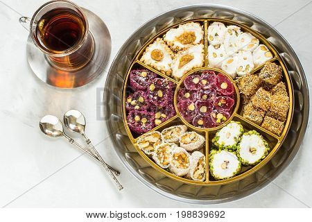 Eastern sweets. Assorted traditional Turkish delight (Rahat lokum) on gray stone background. Turkish delight with different nuts and coconut shavings tea in glass (armud) and spoons. Top view