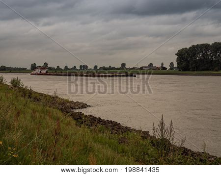big pushing ship drives upstream the rhine Grieth am Rhein Germany on a very cloudy day