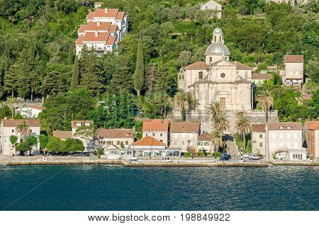 Prcanj. The town's waterfront with a long line of stone villas and the most impressive feat of architecture in Prcanj - the Birth of Our Lady church designed by a Venetian architect Bernardino Maccaruzzi. The church has a monumental baroque facade with Co