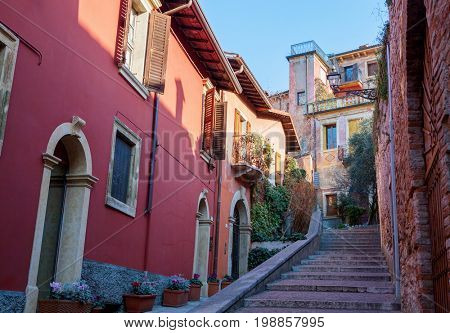 Narrow street with colorful houses along the way to the Castel San Pietro,  Verona, Italy.