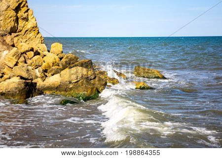 Waves beat against stones on a sunny day