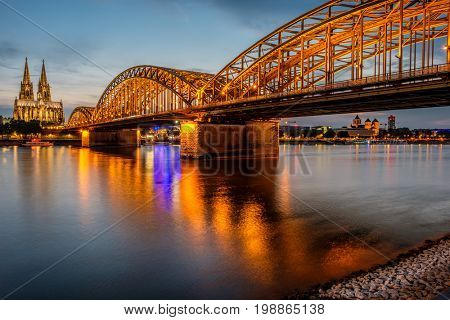 Night View of Cologne Cathedral (Kolner Dom) and Rhine river under the Hohenzollern Bridge, Cologne city skyline at night, North Rhine Westphalia region, Germany.