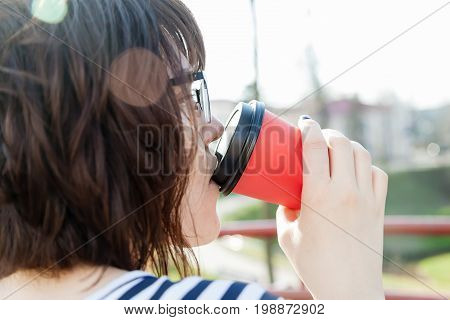 A girl in a striped T-shirt is drinking coffee with a blurred background