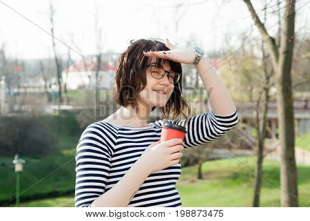 A girl in a striped T-shirt is drinking coffee with a blurred background