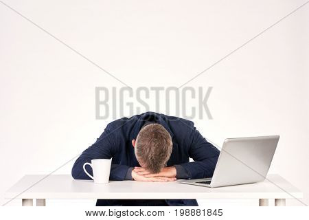 Portrait of middle-aged businessman sitting at office desk with laptop on it