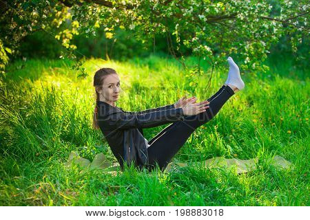 Woman Doing Yoga Outdoors On Green Grass