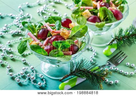 Delicious festive salad with fresh corn salad grapes sausage croutons and nuts Siberian pine in glass vases. Bright color and taste. Colorful salad for Christmas