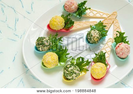 Small snack balls on serving spoons. Tasty balls of cream cheese with aromatic herbs surimi garlic and egg. Delicious appetizer for party or banquet. Festive food
