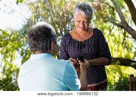 Senior man proposing woman by gifting ring in garden