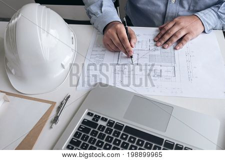 Engineering or Creative architect in construction project Engineers hands working on construction blueprint and building model at a workplace in office Building and architecture concept.