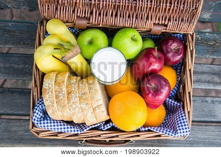 Various Fresh Ripe Fruits In A Wicker Basket On Wooden Table Banana Green And Red Apples Sliced Whol