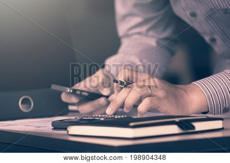 Businessman Calculate About Financial Report And Using Moblie Phone For Searching Data Result In Roo