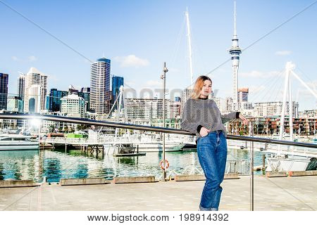 outdoor portrait of young happy smiling teen girl enjoying her trip to auckland, on city scape reflection background