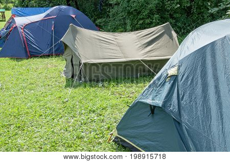 Several different tents standing in a row in the open glade tourist town.