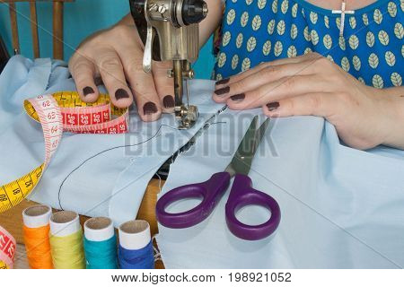 closeup of woman hands sewing yellow cloth outdoors. Woman's Hand Sewing Quilt