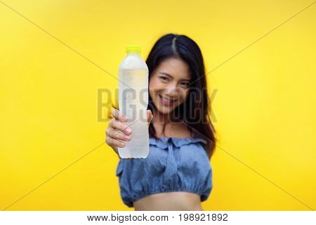 Young girl asian holding pure water bottle on yellow background